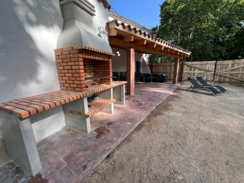 Terrasse extérieure de l'auberge rurale Can Ricós à Vallgorguina avec foyer en brique, sièges et pergola