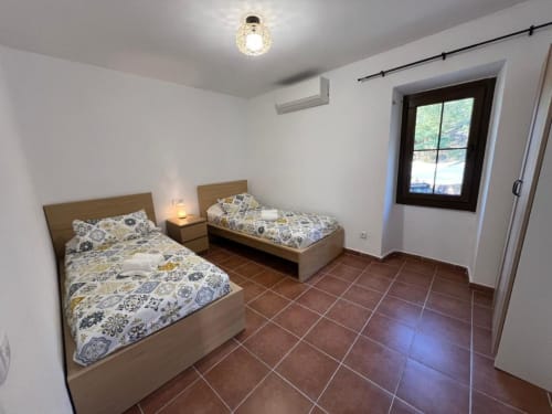 Chambre double à l'auberge rurale Can Ricós à Vallgorguina avec carrelage en terre cuite et vue sur le jardin
