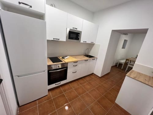Cuisine moderne blanche avec plan de travail en bois et carrelage marron à l'auberge Can Ricós à Vallgorguina, Barcelone
