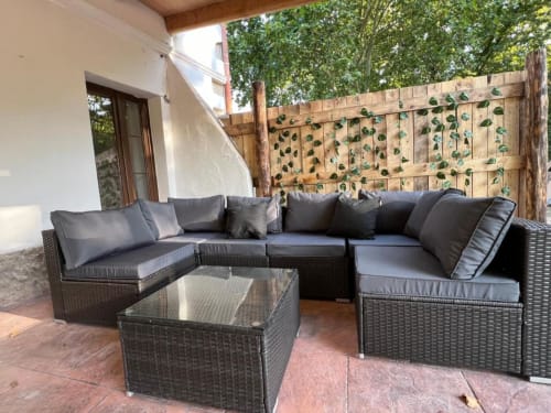 Espace de détente moderne à la terrasse de l'auberge rurale Can Ricós à Vallgorguina, avec mobilier en rotin et mur végétalisé