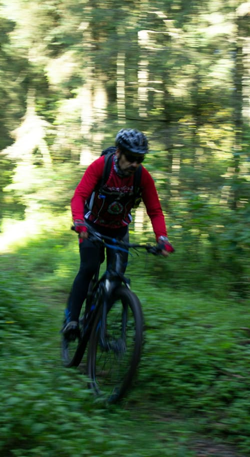 Biker in giacca rossa che percorre un sentiero forestale vicino all'ostello rurale Can Ricós a Vallgorguina, Barcellona