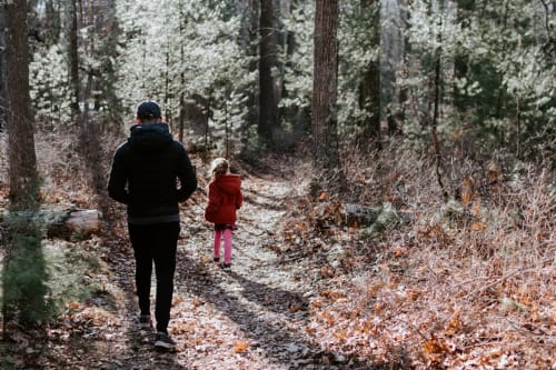 Adulto e bambino che corrono su sentiero forestale presso l'ostello rurale Can Ricós a Vallgorguina, Barcellona
