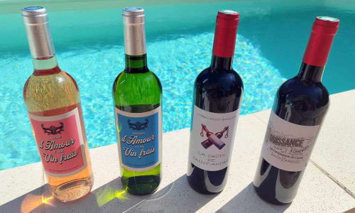 Quatre bouteilles de vin présentées au bord de la piscine à Les Secrets de Winna, une escapade romantique en Nouvelle-Aquitaine