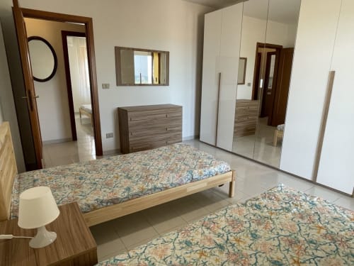 Camera moderna alle Rigiariloo Home Apartments con letti gemelli, armadio a specchio e vista mare a San Giacomo degli Schiavoni