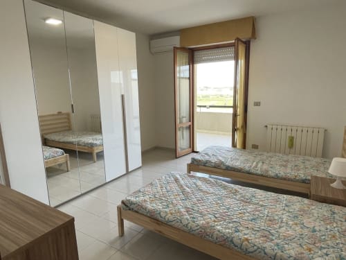 Camera spaziosa negli Rigiariloo Home Apartments con letti gemelli, armadio con specchio e balcone vista mare