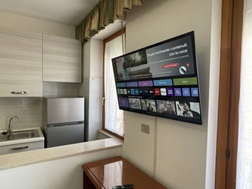 Cucina moderna con TV a parete che mostra il menu streaming negli Appartamenti Rigiariloo Home, San Giacomo degli Schiavoni