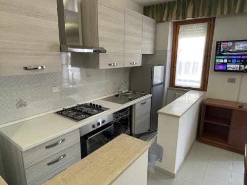 Cucina moderna negli Appartamenti Rigiariloo, San Giacomo degli Schiavoni, con fornello a gas, lavastoviglie e rivestimenti bianchi