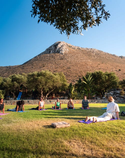 Outdoor yoga class at Villa Freedom in Kokkino Chorio, Crete, with mountain backdrop