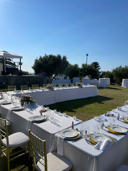 Outdoor wedding reception setup at Villa Freedom in Crete with white-draped tables, gold chairs, and mountain views