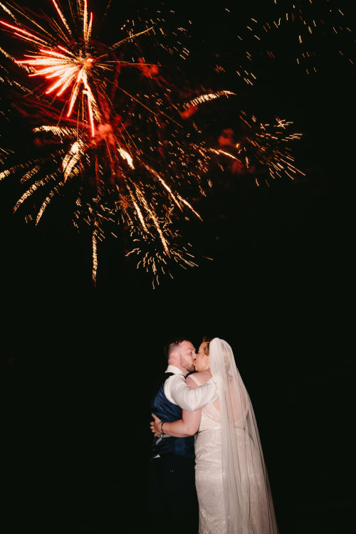 Newlyweds kissing under fireworks at Villa Freedom, a romantic beachside venue in Kokkino Chorio, Crete