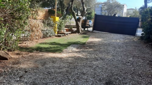 Cour jardin du Camping La Lézardière à La Valette du Var avec allées gravillonnées, oliviers et portail sombre