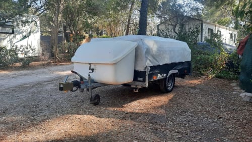 Petite caravane de camping blanche avec housse au Camping La Lézardière à La Valette du Var, ambiance jardin