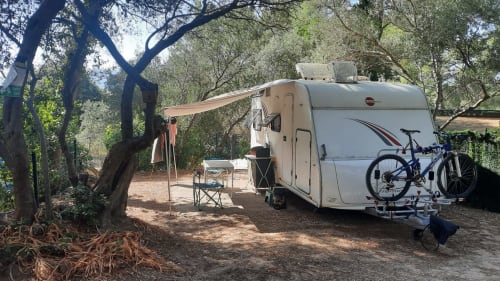Camping La Lézardière avec caravane, auvent, chaises de camping et vélo sous les oliviers à La Valette du