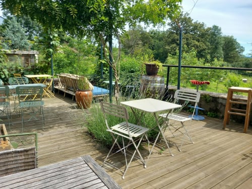 Terrasse de La Maison De Fleurat à Domeyrot avec deck en bois, mobilier de jardin et verdure luxuriante