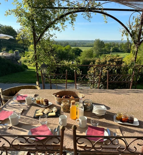 Table de salle à manger en plein air à La Maison De Fleurat avec vue sur la campagne de Domeyrot, France