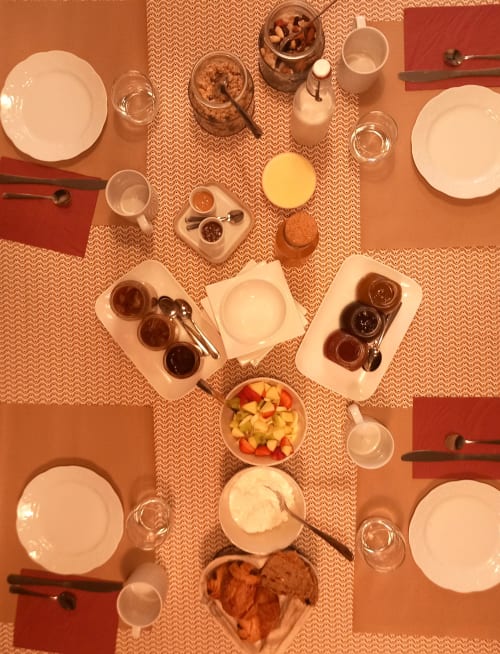 Vue de dessus de la table du petit-déjeuner à La Maison De Fleurat avec assiettes, confitures, jus et fruits frais à Domeyrot