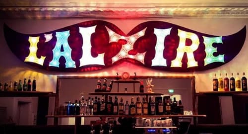 Bar La Maison De Fleurat à Domeyrot avec enseigne néon 'La Flore' éclatante et vitrine de bouteilles illuminée