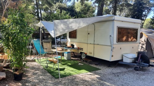 Caravane vintage avec auvent au Camping La Lézardière à La Valette du Var, entourée d'arbres et équipements de camping