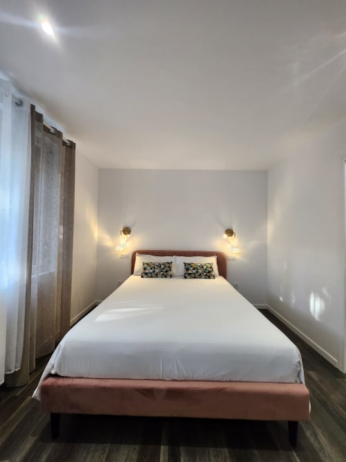 Habitació moderna a l'Appart Hôtel Panambi a Chevilly-Larue amb llit queen, il·luminació càlida i decoració contemporània