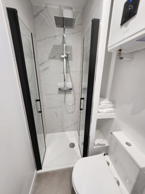 Salle de bain moderne à l'Appart Hôtel Panambi avec douche à l'italienne, carrelage marbre et sanitaires blancs à Chevilly-Larue