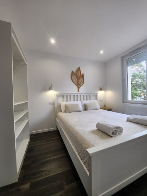 Chambre moderne à l'Appart Hôtel Panambi avec lit blanc, étagères, vue jardin et décoration minimaliste