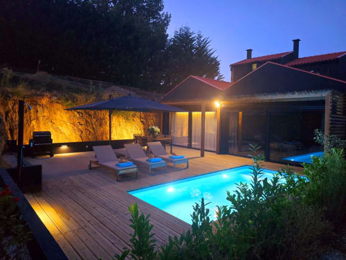 Terraço iluminado à beira da piscina na villa Em Xisto em Góis com espreguiçadeiras, piscina azul-iluminada e design moderno