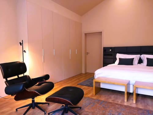 Quarto moderno da villa Em Xisto na serra de Góis com paredes rosa, poltrona preta e cama king com comodidades