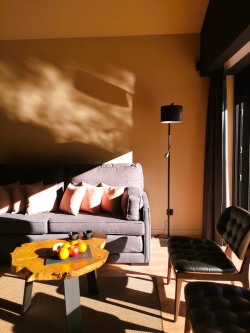Sala de estar contemporânea aconchegante com paredes laranja, sofá cinzento, mesa de madeira, cadeira preta e luz natural em Em Xisto mountain