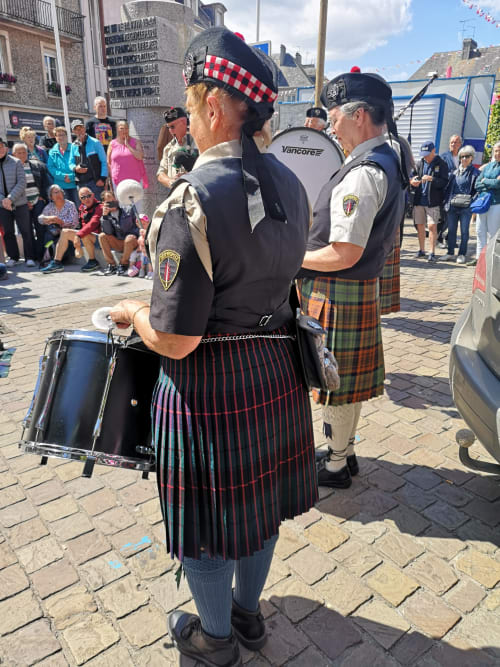 Scottish bagpiper in traditional kilt performs at Isigny-sur-Mer waterfront event