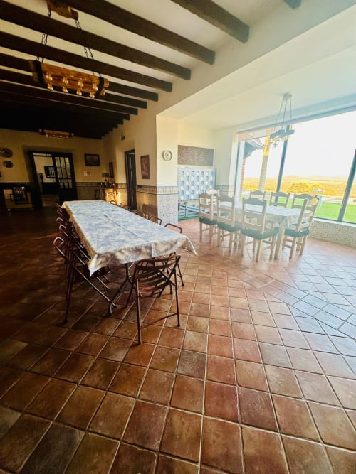 Comedor espacioso de casa rural con baldosas de terracota, vigas vistas y vistas a las montañas en Mérida