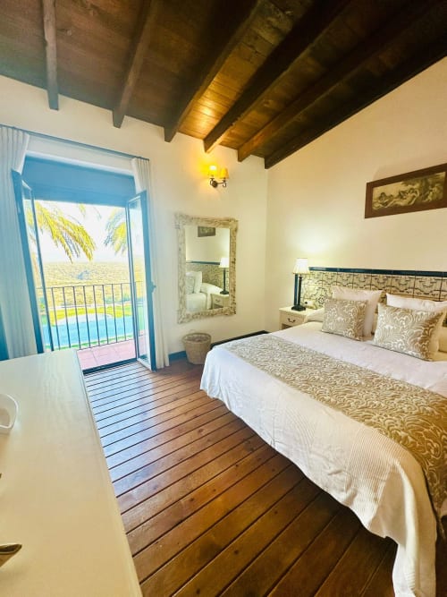 Dormitorio acogedor en Mérida con vigas de madera, cama queen, balcón con vistas a montañas y palmeras