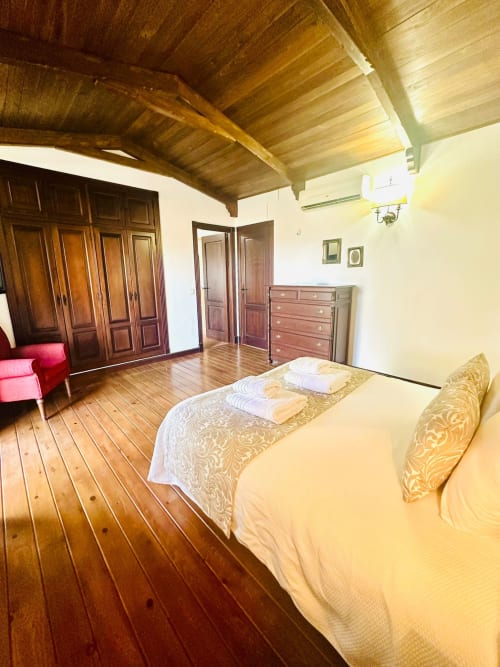 Amplia habitación de cabaña en Mérida con vigas de madera, cama doble, armario de madera y vistas a la montaña