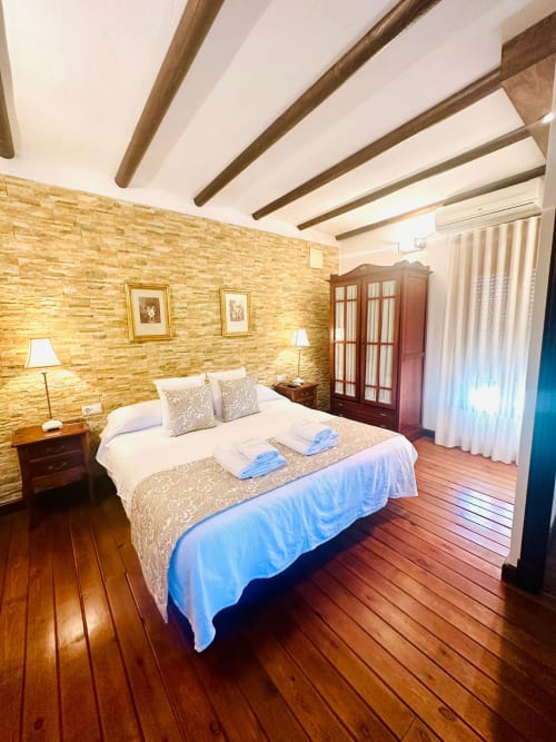 Amplio dormitorio de cabaña en Mérida con paredes de ladrillo visto, vigas de madera, pisos de madera noble y vistas a las montañas