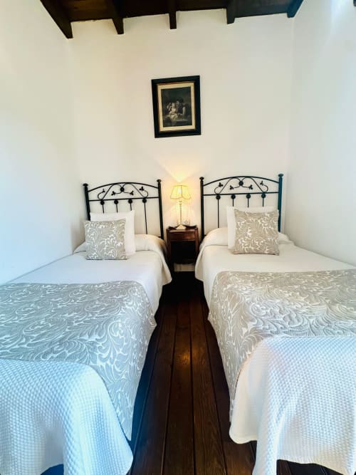 Dormitorio doble en cabaña de Mérida con camas de hierro ornamentadas, ropa de cama estampada y vistas a la montaña
