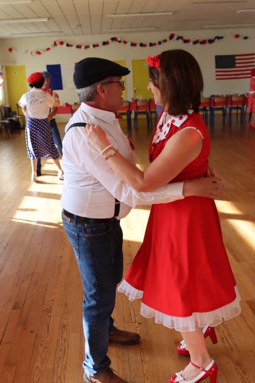 Couple dancing at 1950s-themed event in Normandy hotel hall with American flag decorations