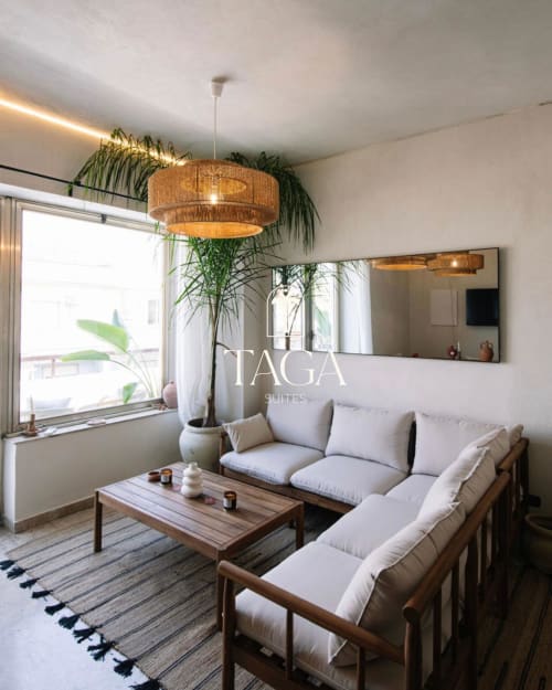 Soggiorno moderno di Tagasuites Catania con divano beige, lampada a sospensione in rattan e vista sulla città