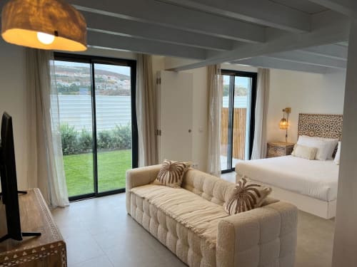 Suíte moderna da villa com vista para o mar, sofá e cama em tons de bege na Casa Zavial, Bordeira Portugal