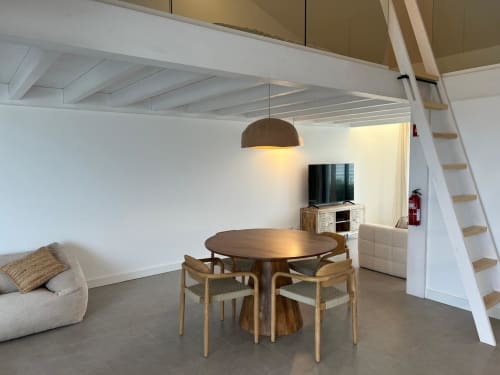 Moderna sala de estar em mezzanino da villa Casa Zavial em Bordeira com mesa de jantar redonda, cadeiras de madeira e luminárias pendentes.