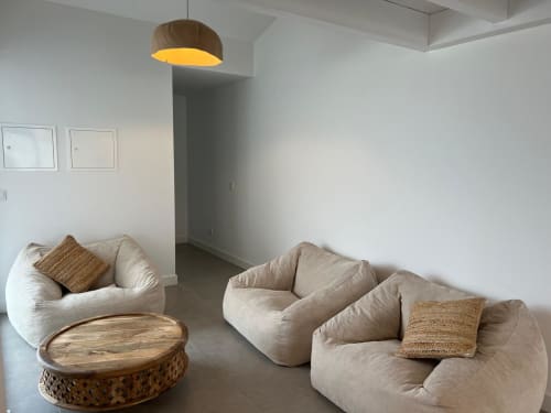 Sala de estar moderna com pufes em tons creme, mesa de apoio em madeira e luminária pendente na villa Casa Zavial, Bordeira Portugal