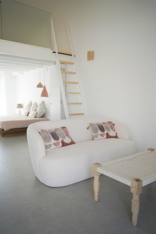 Sala de estar moderna na villa Casa Barranco em Bordeira com sofá branco curvo, mesa de madeira e quarto mezanino com vista para o mar