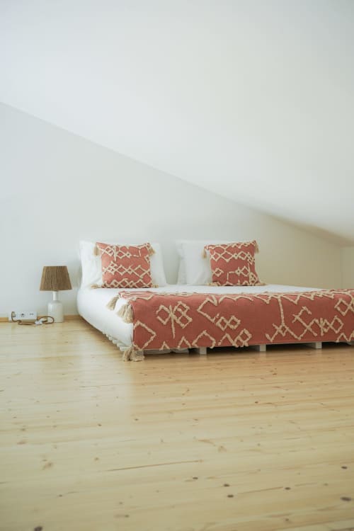 Quarto minimalista com roupa de cama em tons de terracota e almofadas brancas sobre piso de madeira na villa Casa Barranco