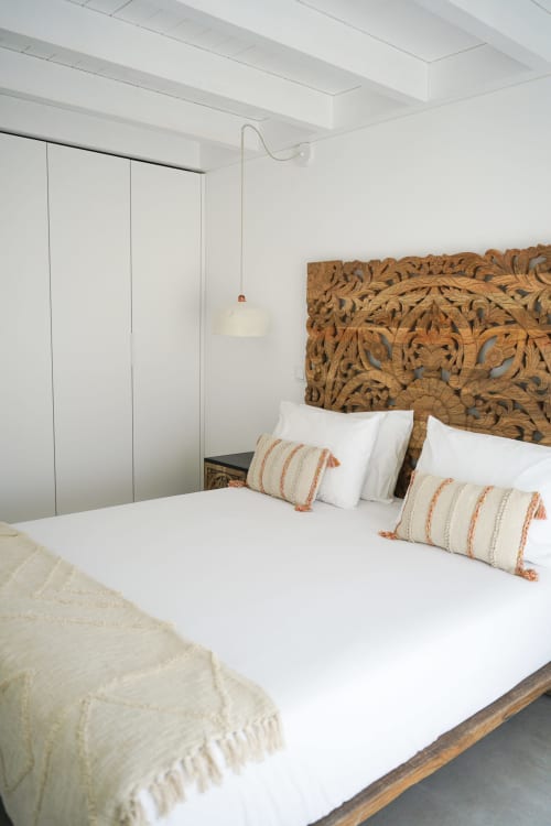 Bright modern bedroom in Casa Furnas villa with carved wooden headboard, white bedding, striped pillows, and wall-mounted