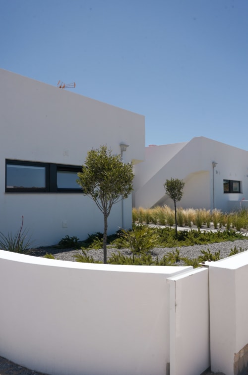 Vila moderna branca Casa Furnas em Bordeira com jardim paisagístico, palmeiras e caminho de pedra sob céu azul cristalino