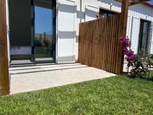 Terraço da villa Casa Bordeira em Bordeira com cerca de privacidade em madeira, jardim bem cuidado, flores magenta e vista para o oceano, Portugal