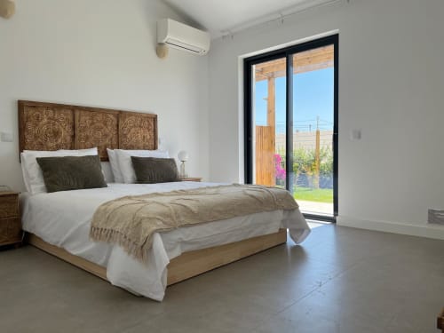Bright bedroom in Casa Bordeira villa, Bordeira with sea view, wooden headboard, white bedding, and garden access through