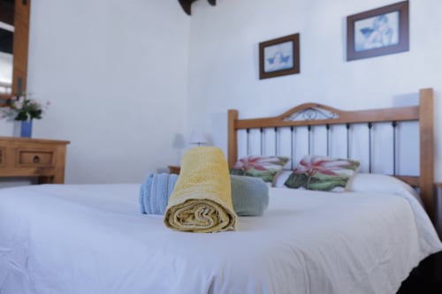 Rolled yellow towel on bed at Casonas de marengo cottage in Icod de los Vinos with wooden headboard and mountain views