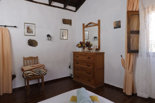 Rustic bedroom at Casonas de Marengo with wooden furniture, mirror, framed art, and mountain views in Icod de los Vinos