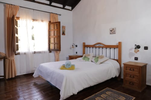 Bright bedroom at Casonas de Marengo in Icod de los Vinos with wooden bed, white linens, and mountain views through large