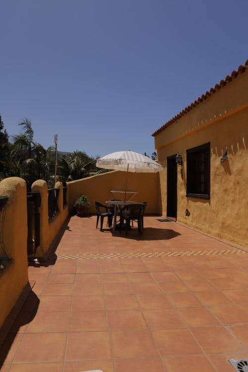 Sunny terrace at Casonas de Marengo cottage with table, white umbrella, and mountain views in Icod de los Vinos
