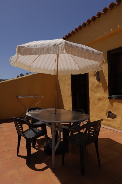 Terrace seating area at Casonas de marengo with round table, black chairs, and cream umbrella under clear sky